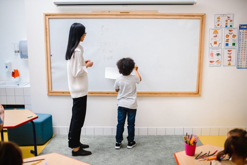 Woman and a Boy Standing by a Whiteboard in a Classroom